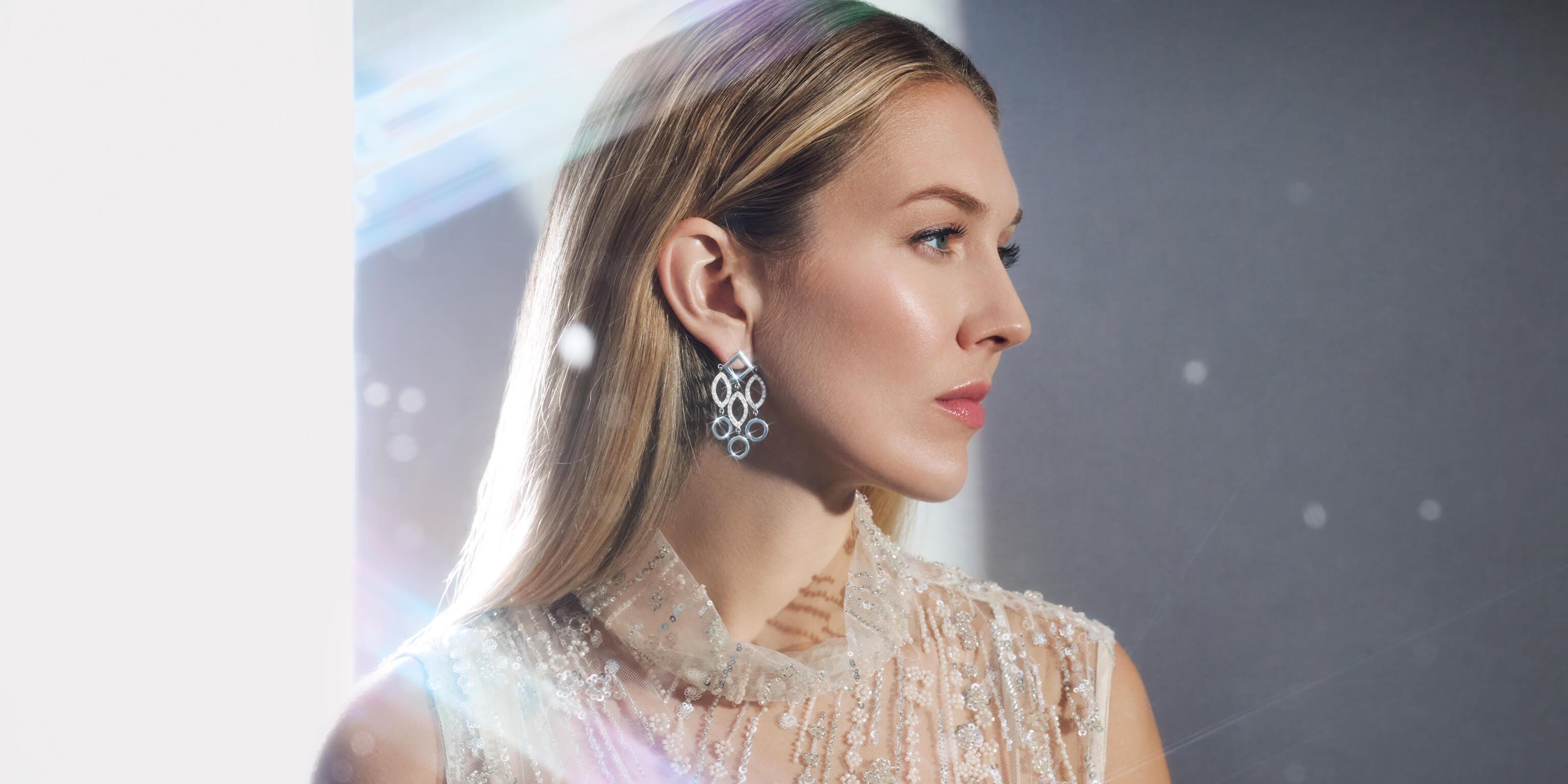 Model wears handcrafted fine jewellery earrings in 18ct white gold with diamond surrounded by falling snow. The perfect statement earrings for the festive season.