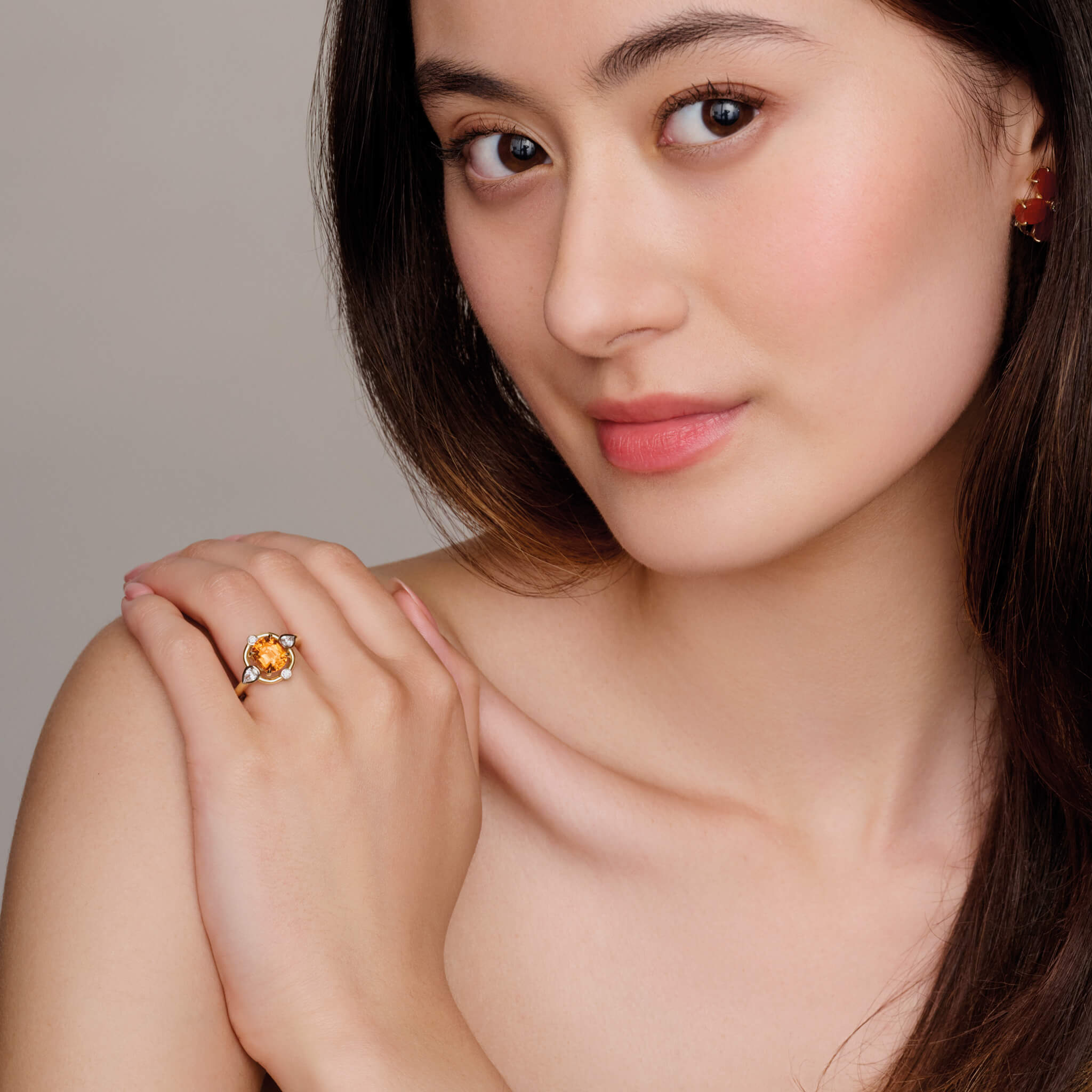 Model wearing handmade 18ct yellow gold cocktail ring featuring a mandarin garnet at its centre, surrounded by four smaller diamonds, two teardrop-shaped, january birthstone