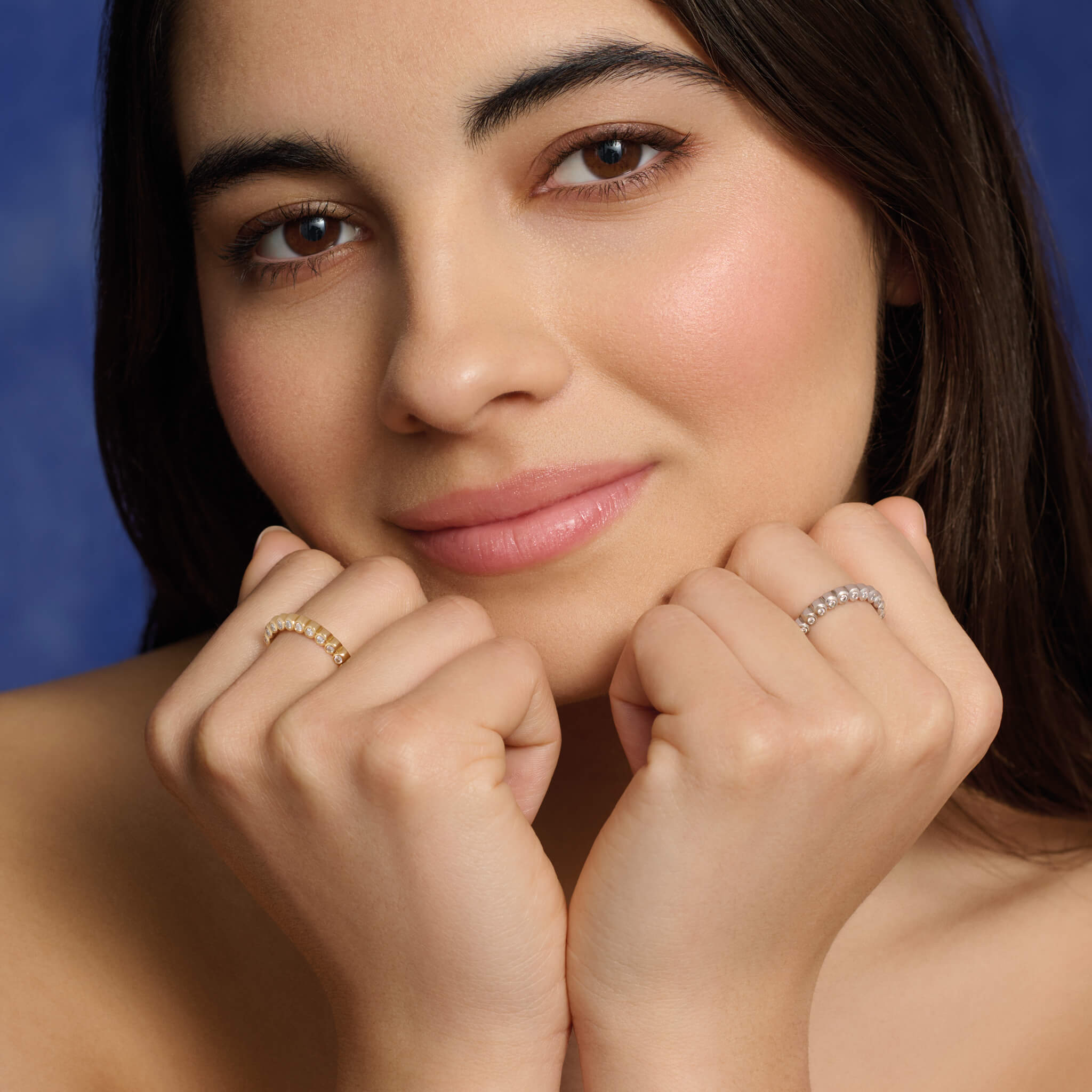 Model wearing handcrafted 18ct gold eternity rings with diamonds on the side of the shank and smooth ridges along the top.