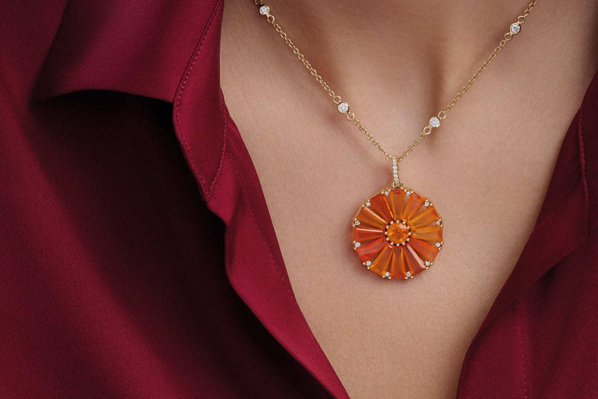 Model wears fire opal and diamond pendant featuring fire opal from Mexico, renown for its vibrant orange colour. Worn with a red shirt on a diamond chain.