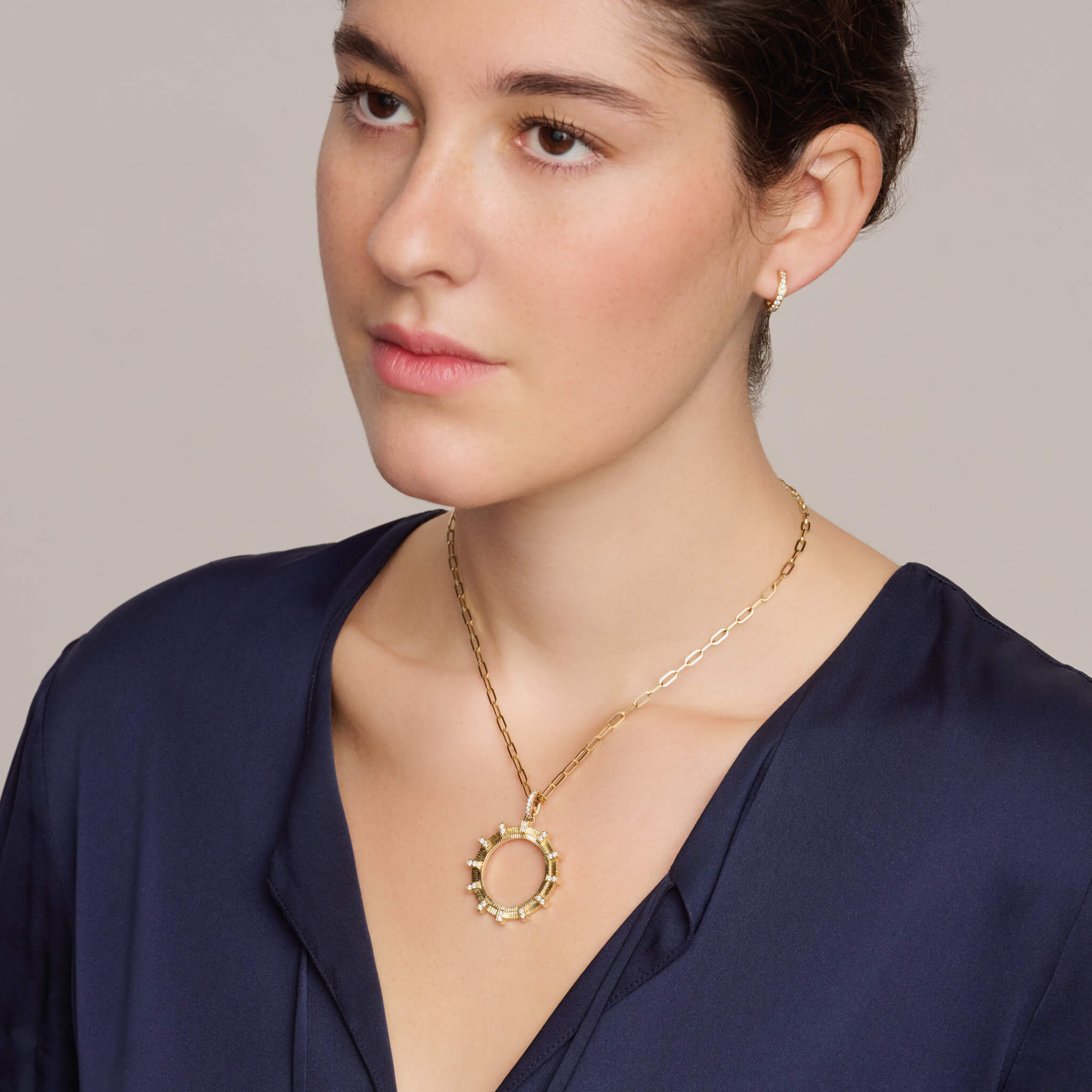 Model wears handcrafted Kipoi necklace pendant in yellow gold with diamond pave. Inspired by the stone bridges of Zagori in northern Greece.
