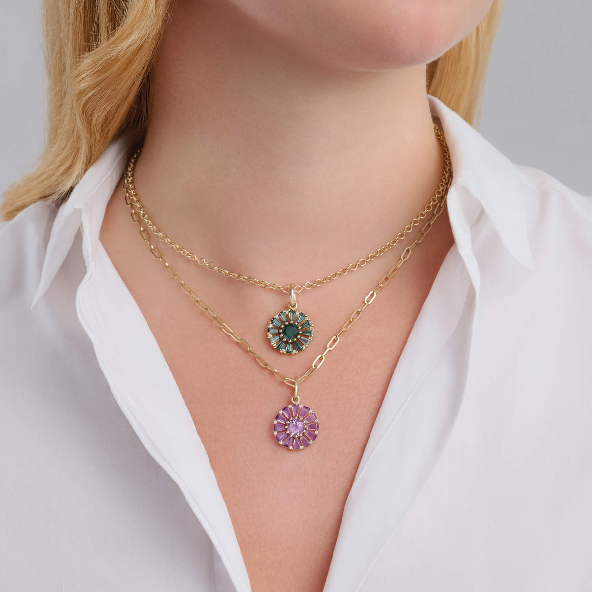 Model wears two Roi Soleil small pendants one with green/blue sapphire and one with purple amethyst, both with diamonds. The birthstones of February and September.