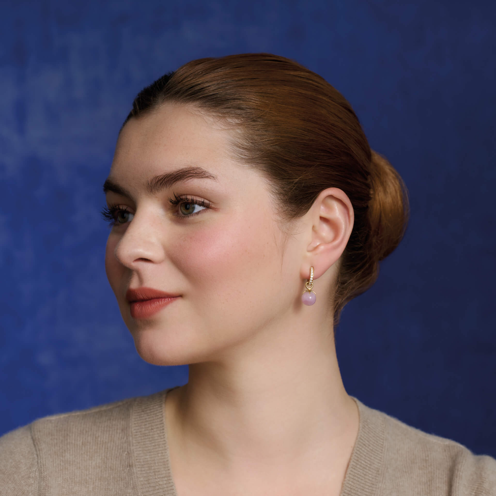 Model wears handcrafted yellow gold earring drops with round purple kyanite beads.