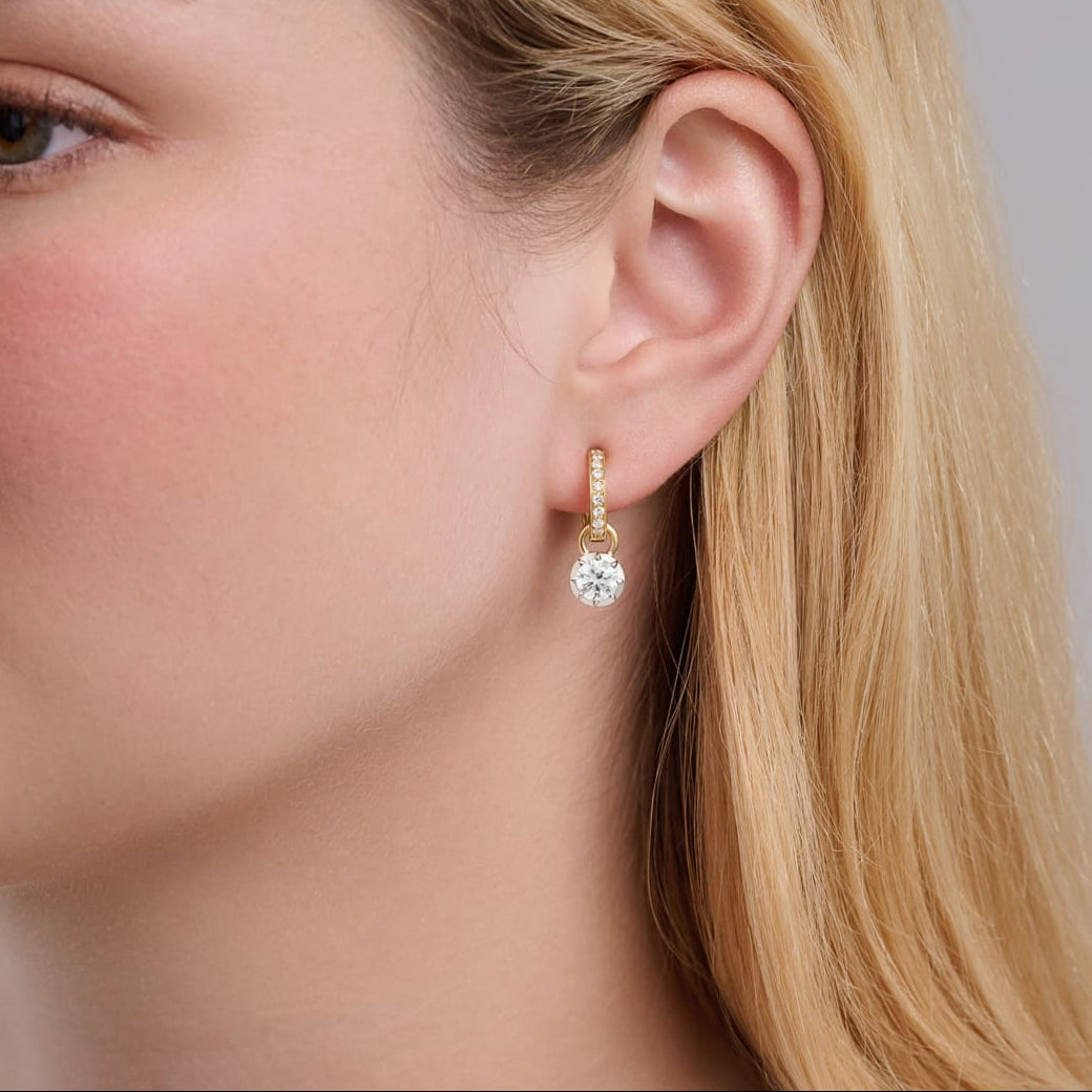 Model wears handcrafted Charlotte earring drops in 18ct yellow and white gold with a certified round brilliant diamond, set in a Georgian-inspired setting