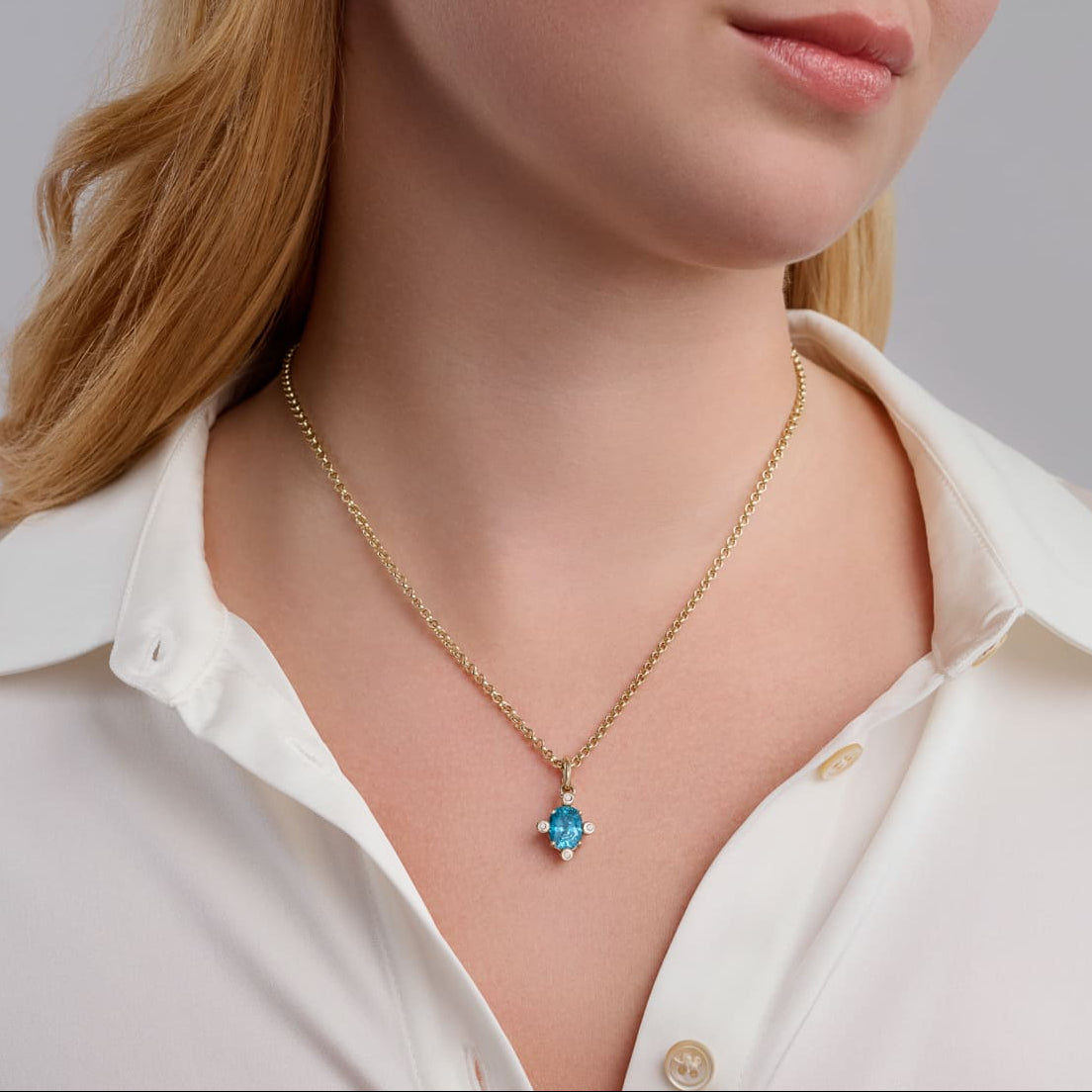 Model wearing handcrafted Compass medium necklace pendant in yellow gold with blue zircon set with four diamonds, December birthstone