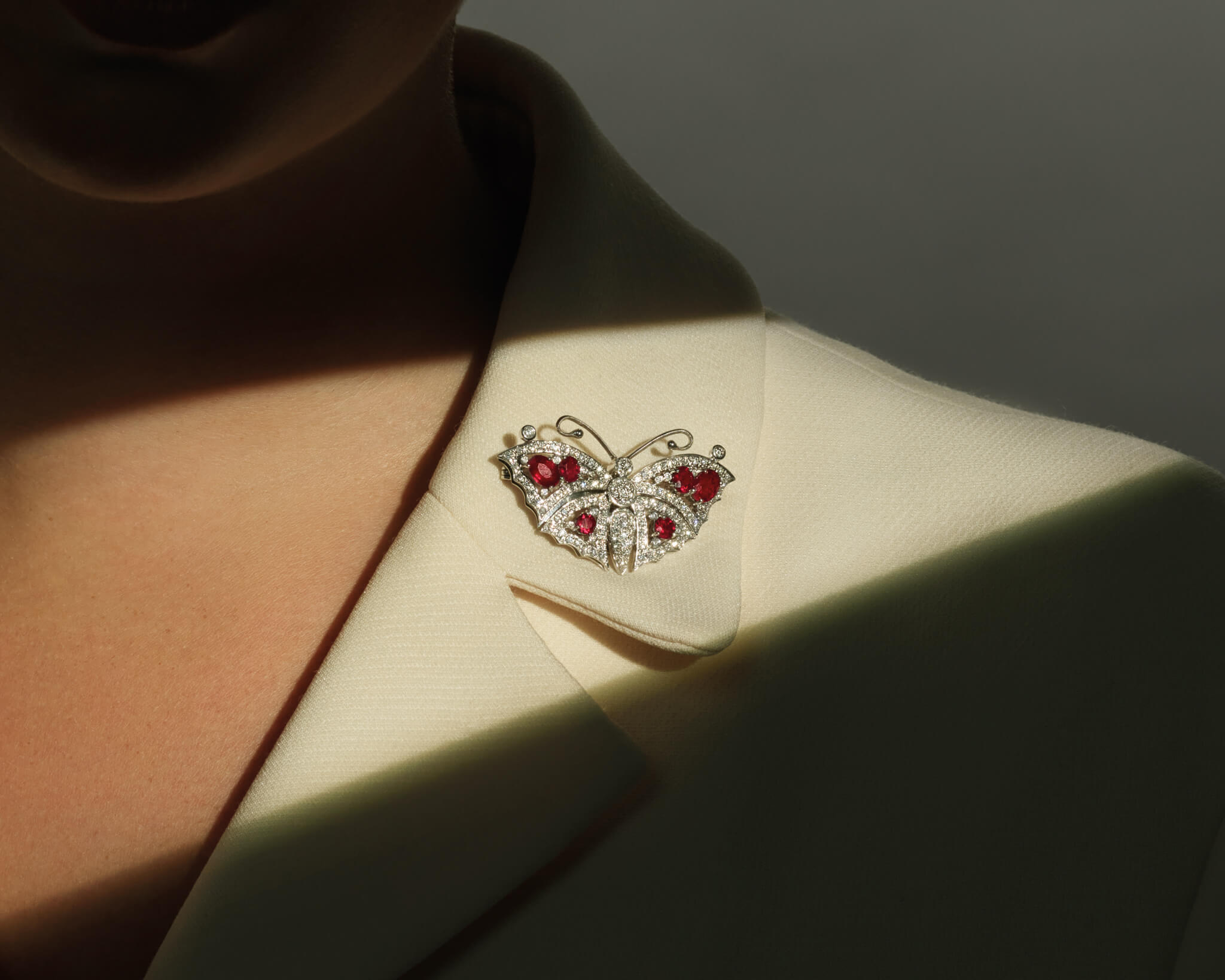 Model wears the Beijing Butterfly brooch in 18ct white gold with ruby and diamonds 