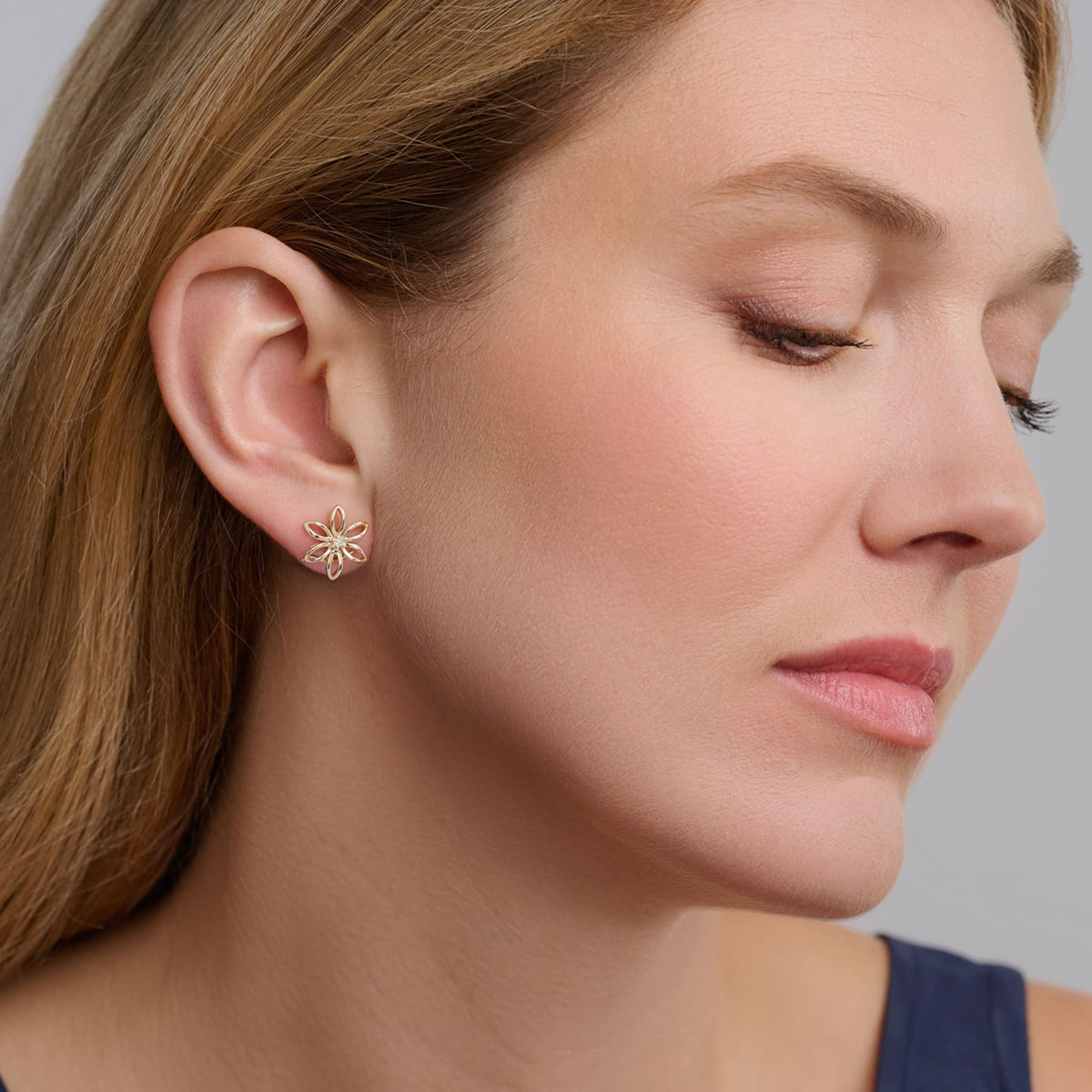 Model wears handcrafted silver flower studs with a central diamond, birthstone of April.