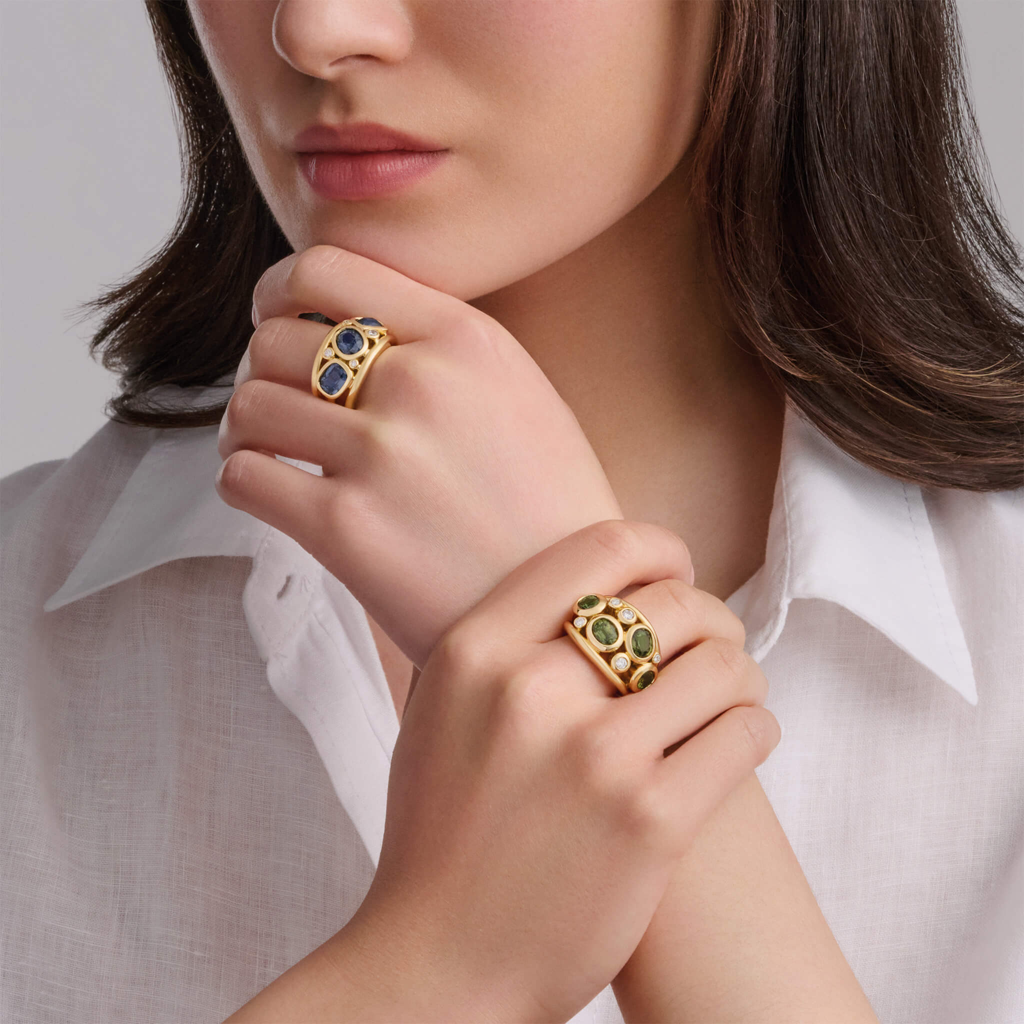 Model wears multi aeneus rings with blue spinel and fine green sapphire and diamonds.