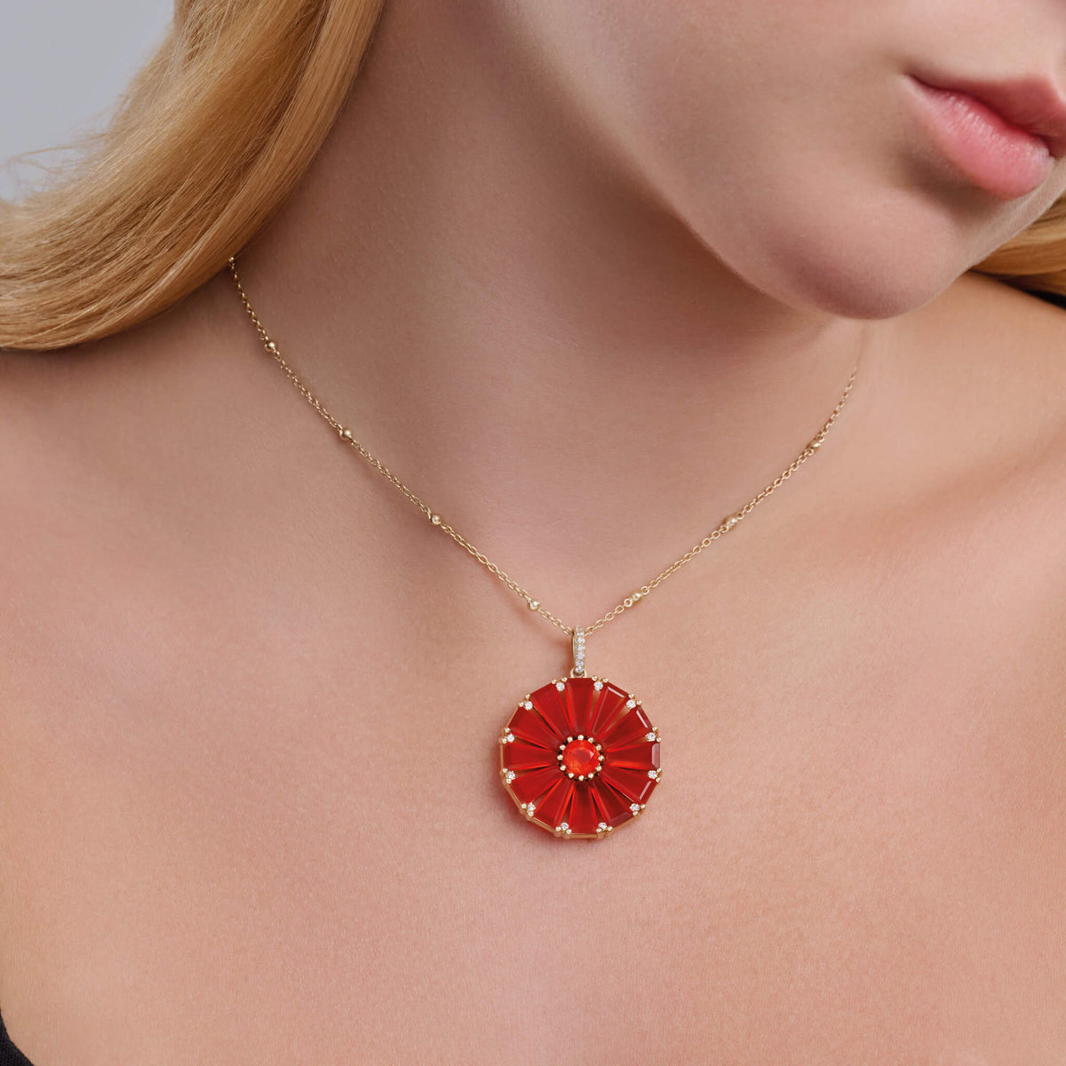 Model wears Roi Soleil necklace pendant handcrafted in 9ct yellow gold with facetted rare orange fire opal, red cornelian and diamond. 