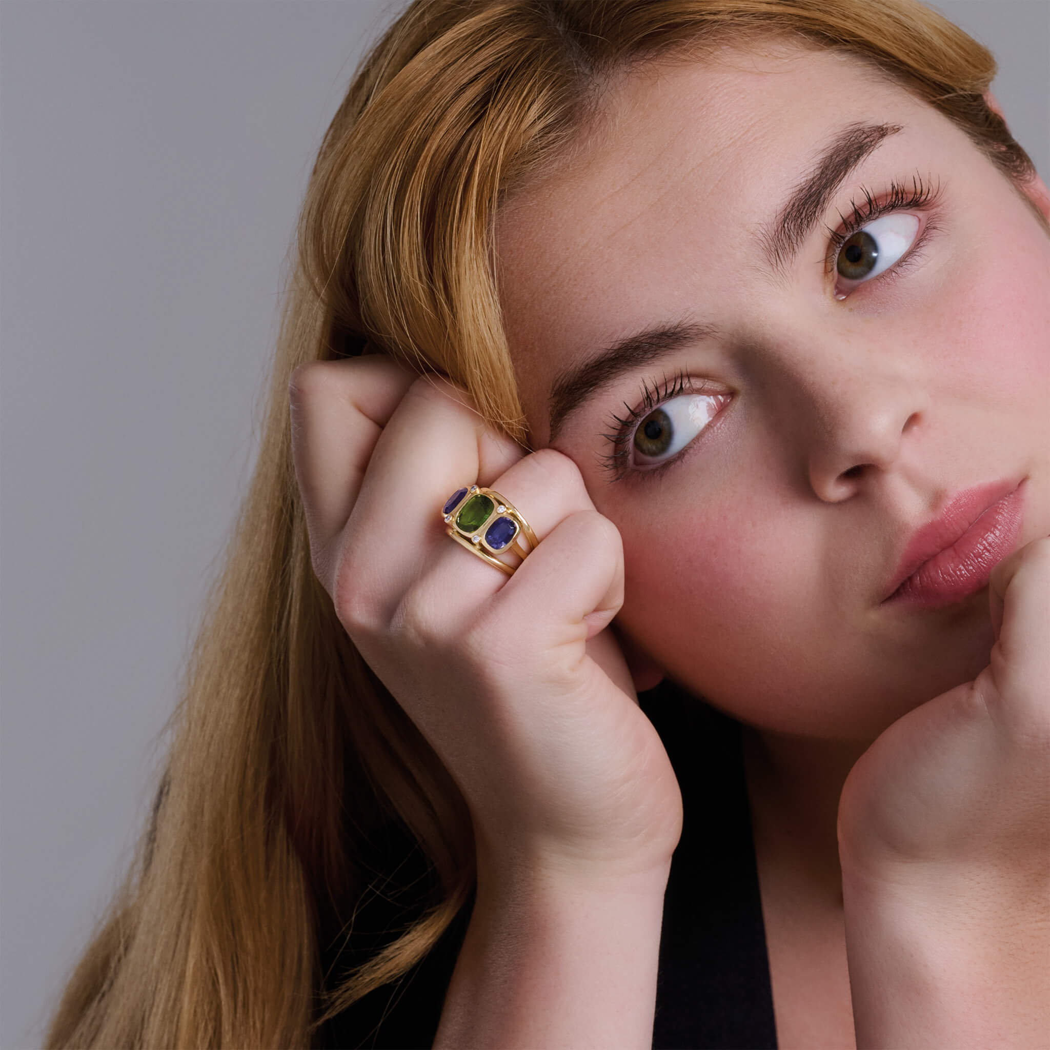 Model wearing a handcrafted 18ct yellow gold ring featuring rectangular shaped gemstones and diamonds.