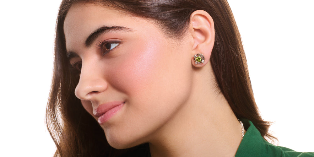 Model wearing handcrafted white gold earring halos with diamonds and peridot stud earrings at the centre, birthstone of August.