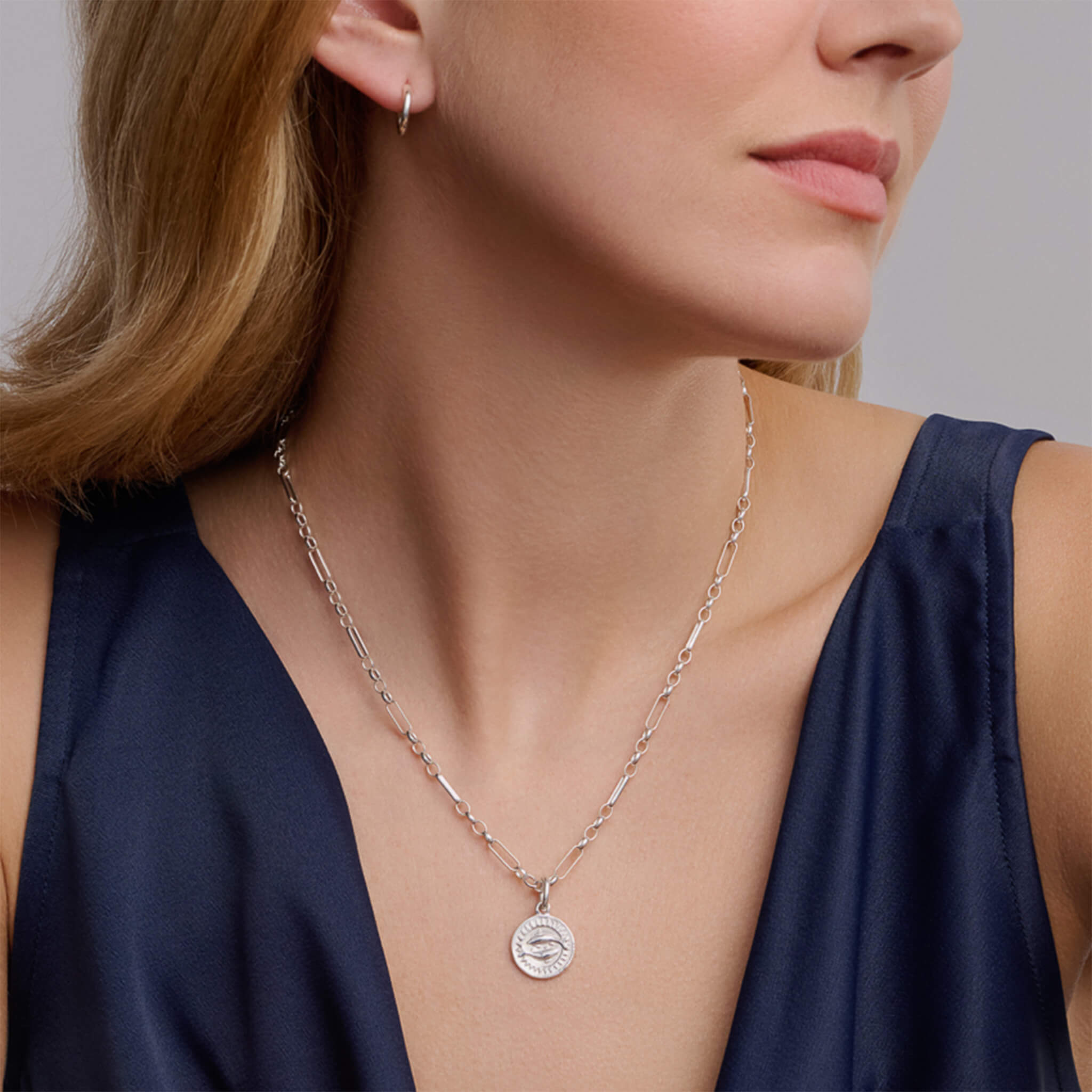 Handcrafted round sterling silver necklace pendant engraved with the zodiac pisces.