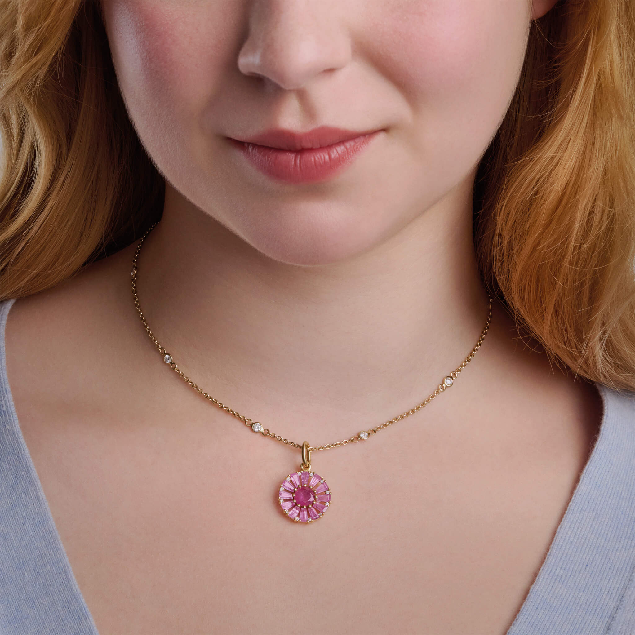 Model wearing two handcrafted necklace pendants in precious metal featuring a circular arrangement of precious stones.