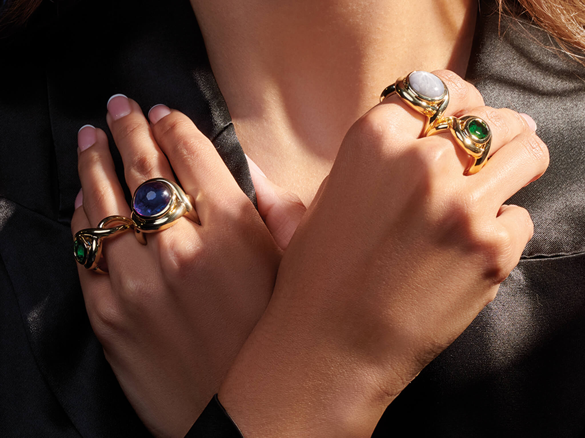 Hands crossed over with different Cassandra Goad Severine cocktail rings on each finger. 