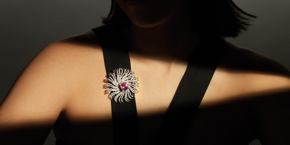 Model in shadows with light shining on her Cassandra Goad Taj Mahal brooch with pink tourmaline centre stone