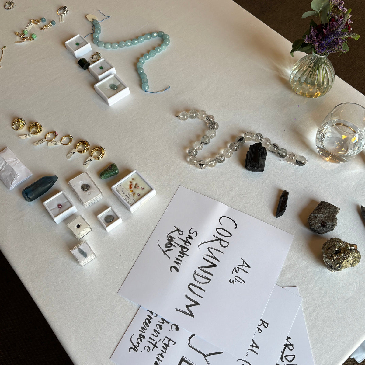 Display of handcrafted silver and yellow gold jewellery and crystals and handwritten paper labels