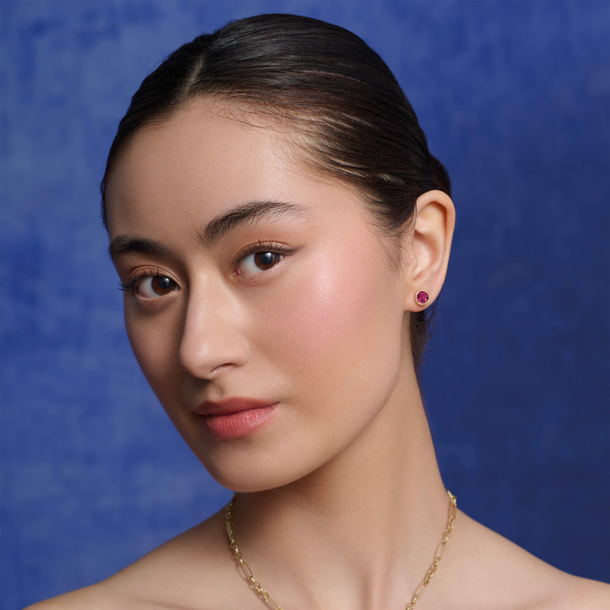 Model wears Cassandra Goad Theresa studs in yellow gold and red garnet.