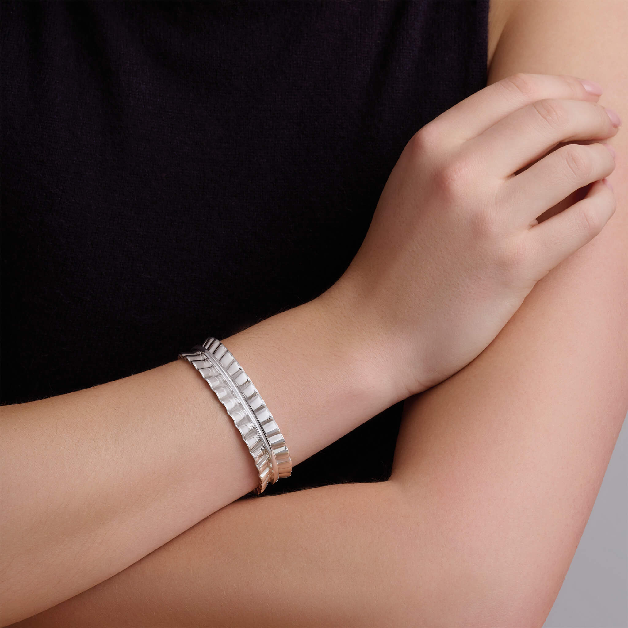 Model wearing a handcrafted sterling silver cuff bracelet featuring an undulating ribbon shape.
